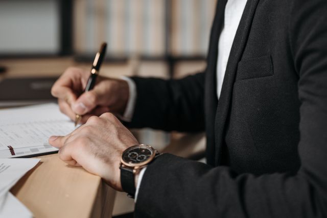 Man in Black Suit Writing on a Paper